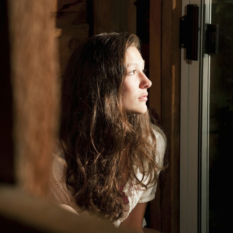 Teenage girl staring out of an open window
